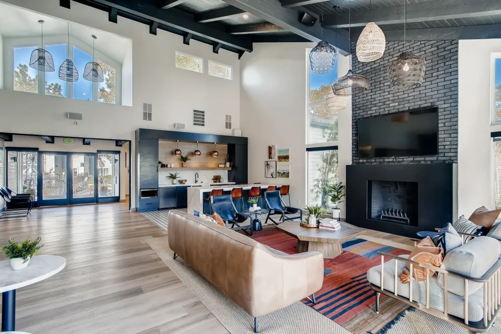 Clubhouse lounge with sofas, fire place, tv, and kitchen