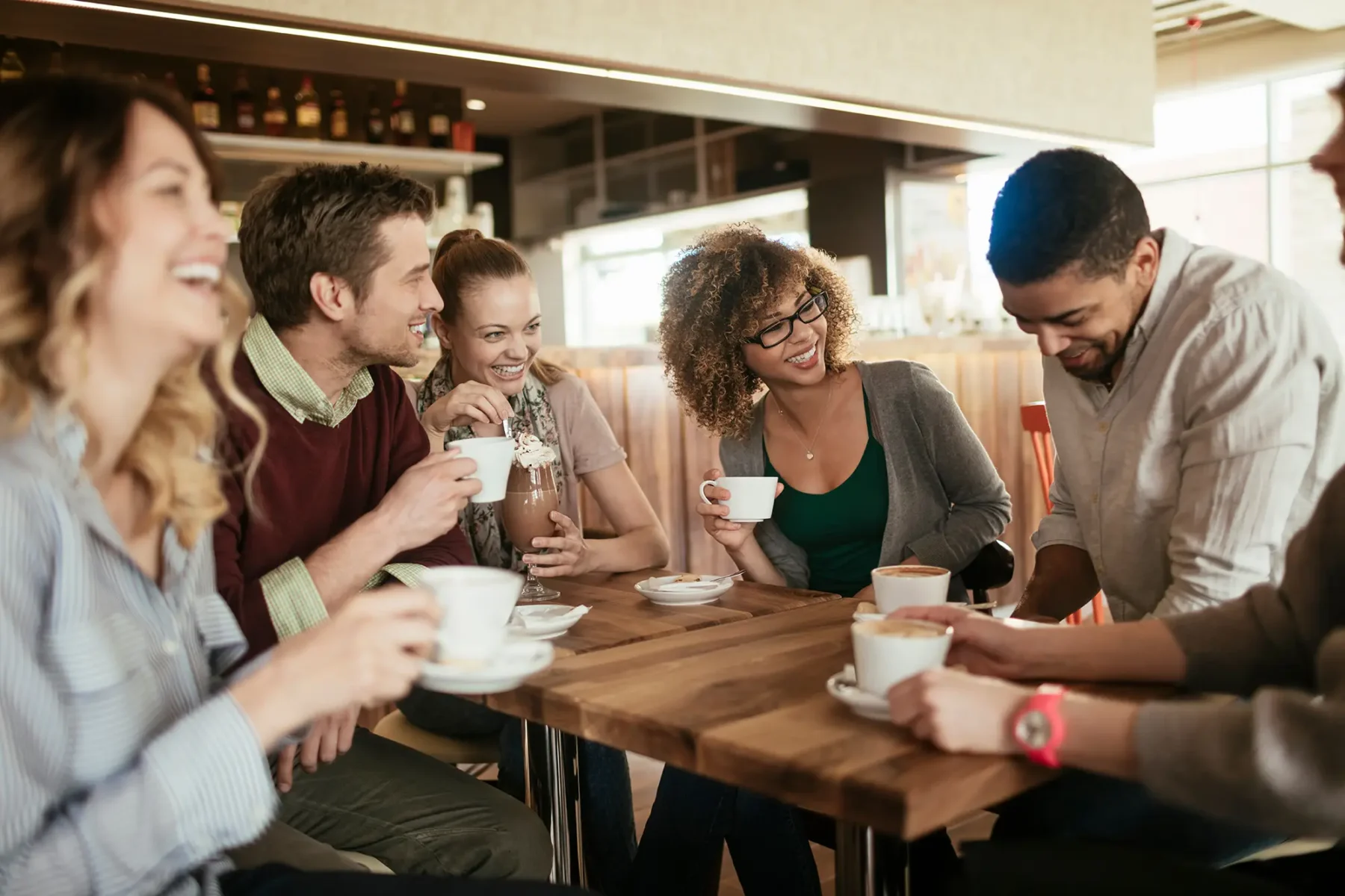 Friends sitting in a cafe drinking coffee and laughing