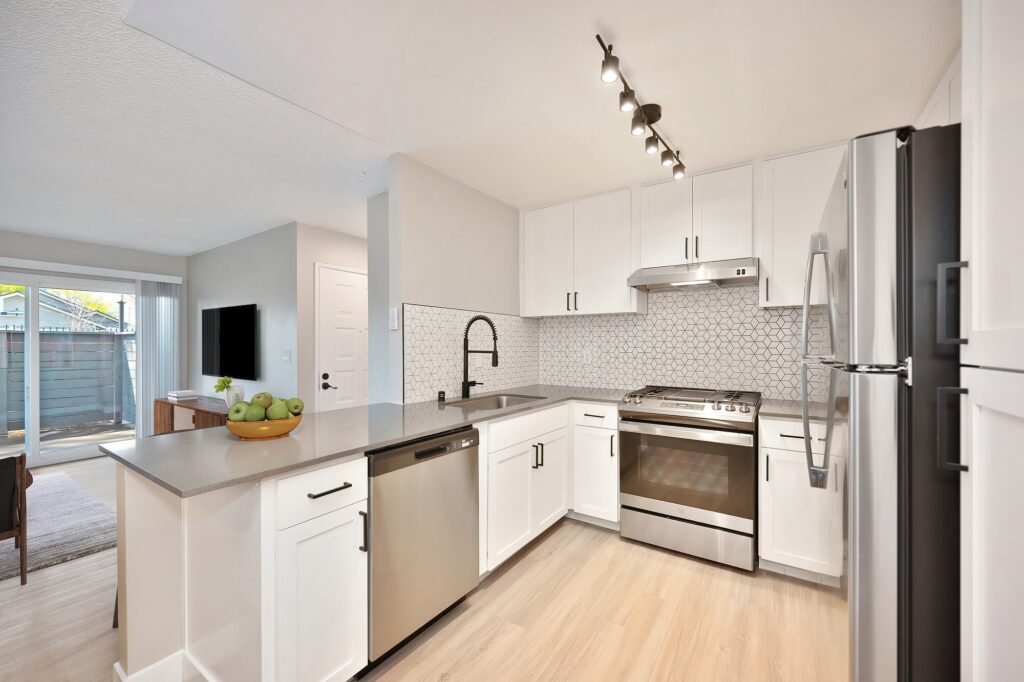 Renovated apartment kitchen with breakfast bar, white cabinets, black accents, and stainless steel appliances.
